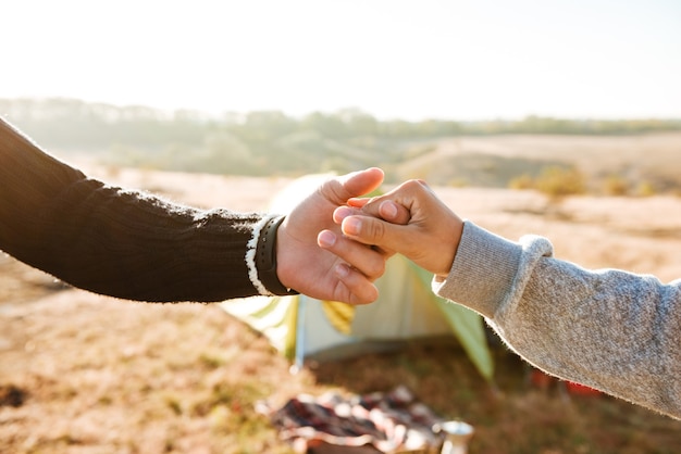 Foto coppia mano nella mano vicino alla tenda. immagine ritagliata