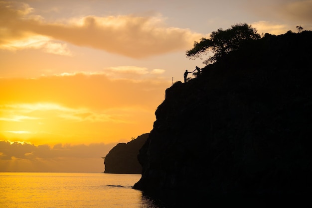 Couple holding hands on a rock by the sea in the bay