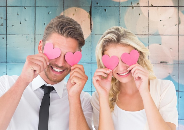 Couple holding hearts over eyes