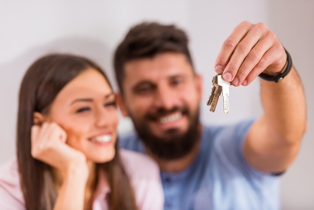 Couple holding keys to new home, moving to a new home.