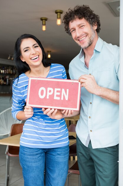 Couple holding open signboard