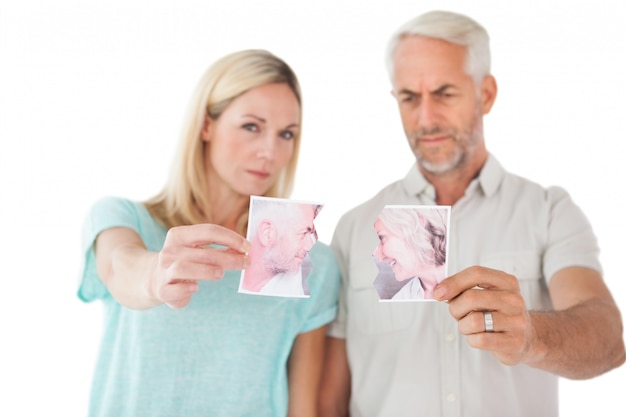 Couple holding two halves of torn photograph