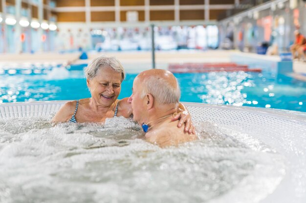 A couple in a hot tub with a swimming pool in the background