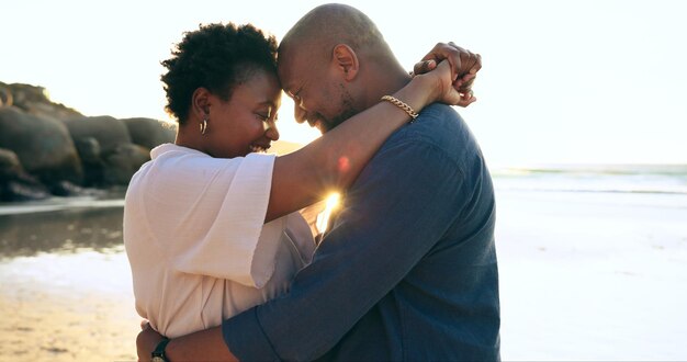 Couple hug and happy on beach with love bonding and sunset for holiday vacation and relationship Black people man or woman with embrace smile and romance by ocean or sea for travel or adventure