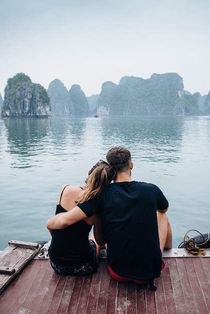 Couple hugging each other on the deck of cruise ship with view on Halong Bay and calm sea. Shoot from the back.