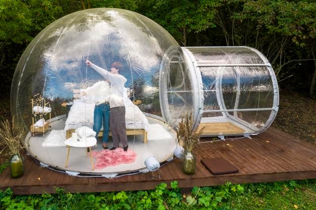 A couple hugging inside a transparent bubble tent at glamping