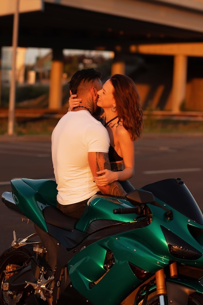 Couple hugging near motorbike at sunset