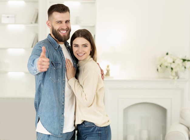 Couple hugging in new apartment man showing thumb up