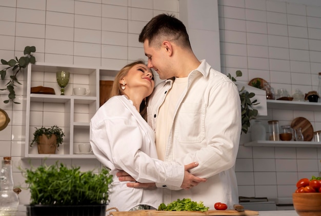 Couple hugging and smiling in kitchen while cooking handsome man and beautiful woman looking at each