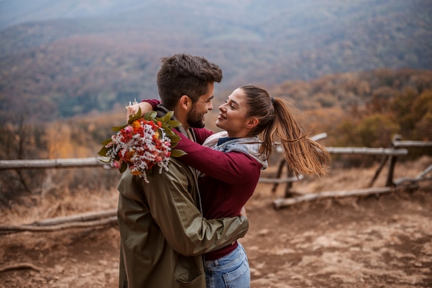 Couple hugging while standing on viewpoint.