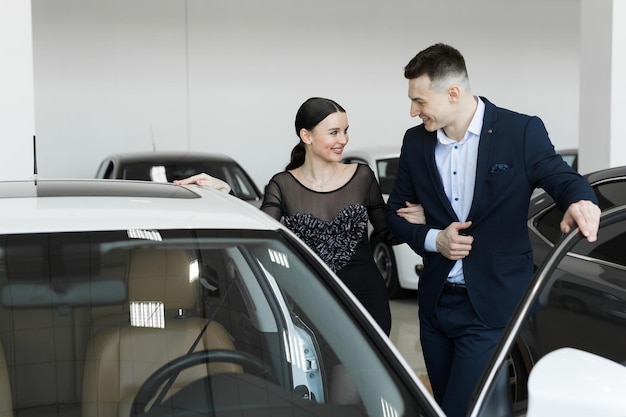 A couple husband and wife choose a car to buy at a car dealership