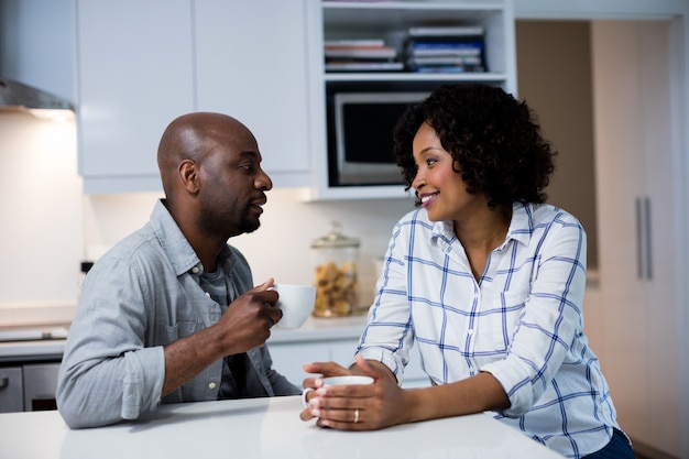 Couple interacting with each other while having coffee in kitchen