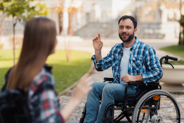 A couple of invalids on wheelchairs met in the park.