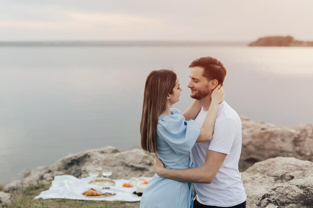 A couple is embracing and having a picnic on the beach.