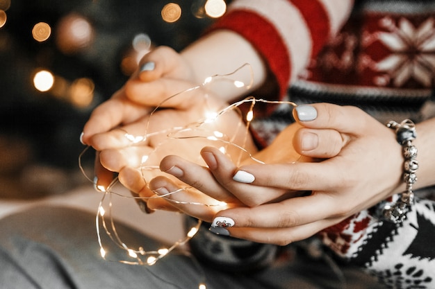 Couple is holding fairy lights with their hands.