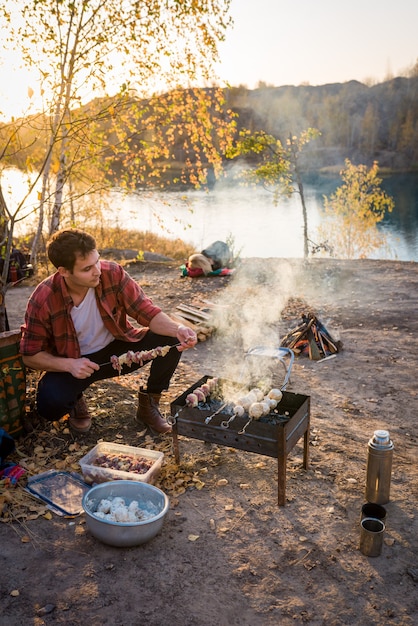 The couple is resting in nature. Man preparing barbecue in nature