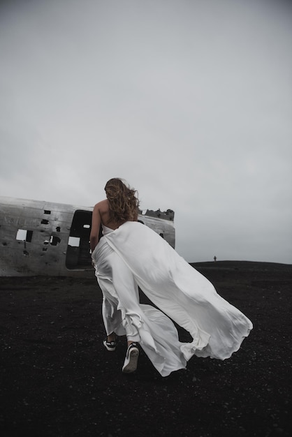 couple is standing near the plane which fell a long time ago black beach