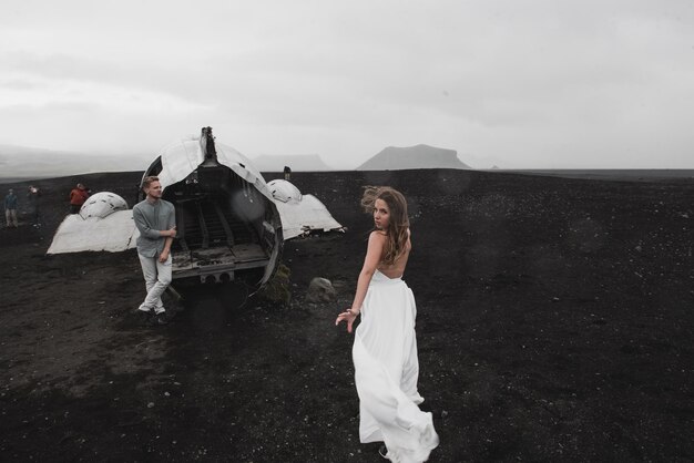 couple is standing near the plane which fell a long time ago black beach