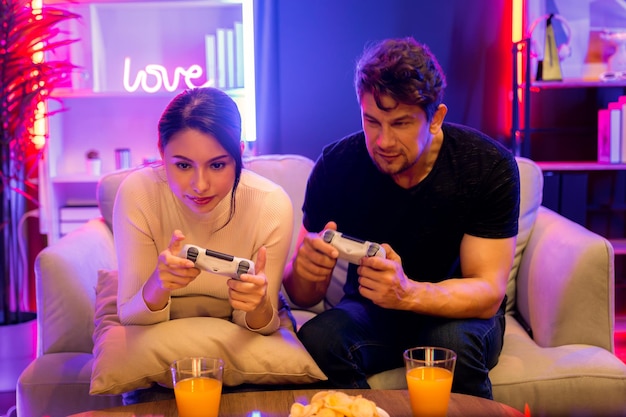 Couple joyful funny playing game using joysticks trying to disturb postulate