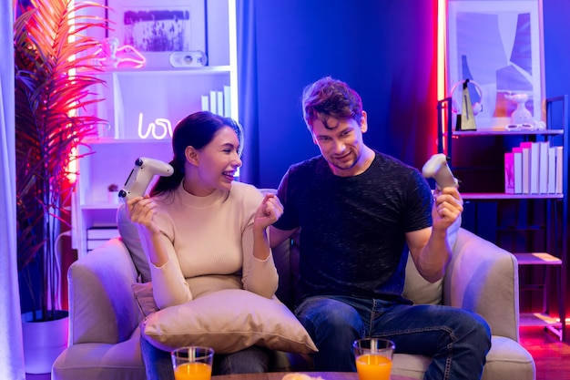 couple joyful player video game on tv using joystick raising fist up postulate
