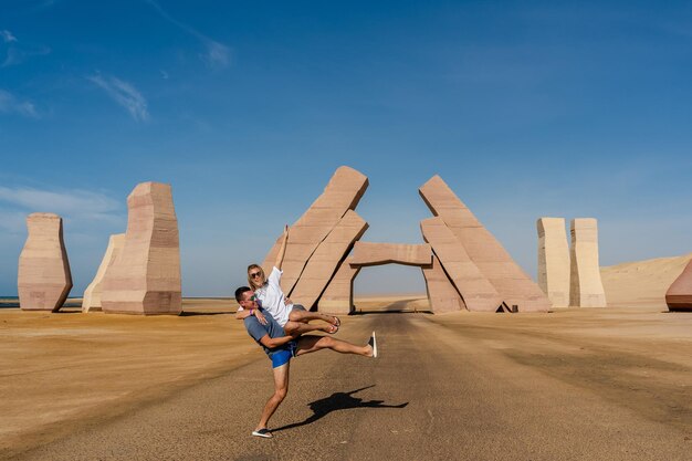 Couple jump near huge Gate of Allah Ras Mohammed national park in Egypt Desert