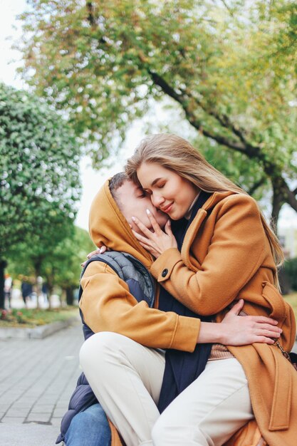 Photo couple kissing against trees at park