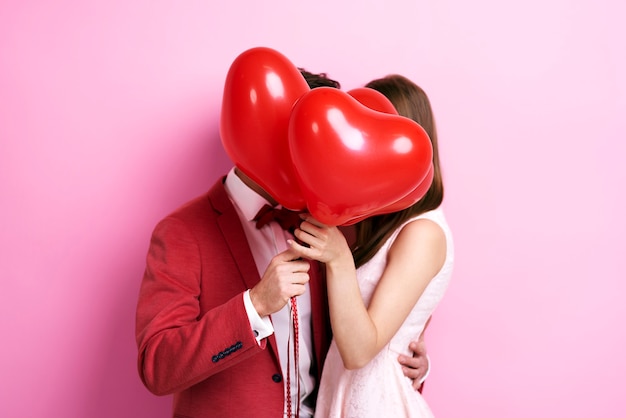 Photo couple kissing behind balloons