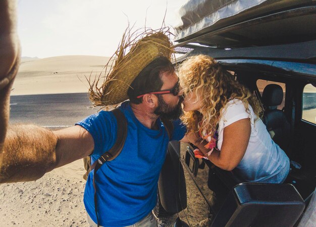 Couple kissing by car on sand in desert