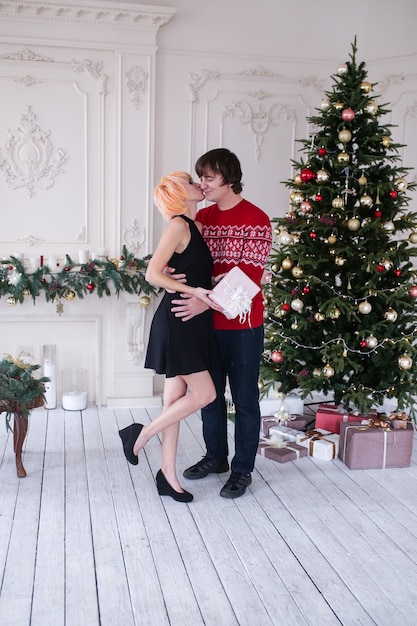 Couple kissing on Christmas time with gifts box in front of the Christmas tree