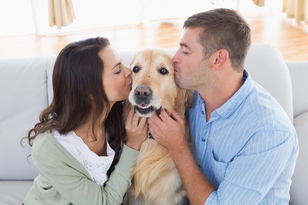 Couple kissing Golden Retriever on sofa