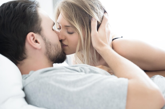 Couple kissing while lying on bed