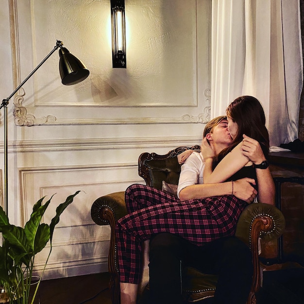 Photo couple kissing while sitting on chair