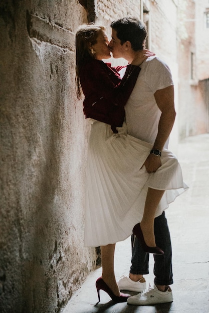 couple kissing while standing against wall