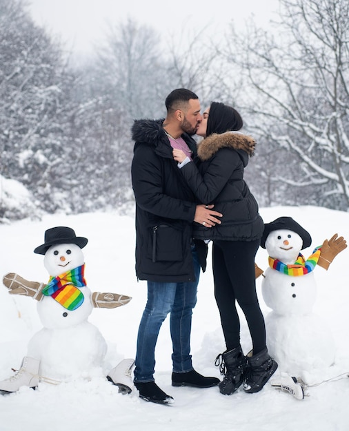 Couple kissing over winter background kiss on christmas background with snowman portrait of lovely c...