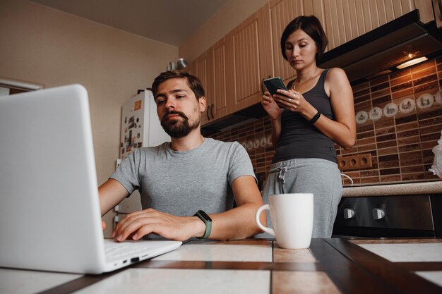 Couple at kitchen reading news and using laptop