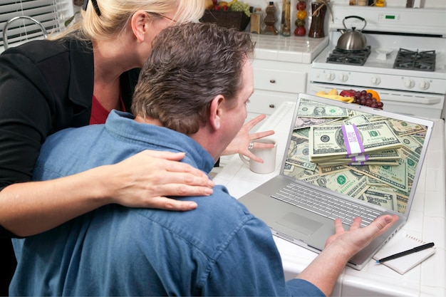 Photo couple in kitchen using laptop money