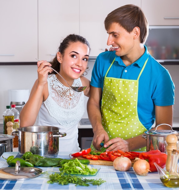 Coppia in cucina con verdure al tavolo