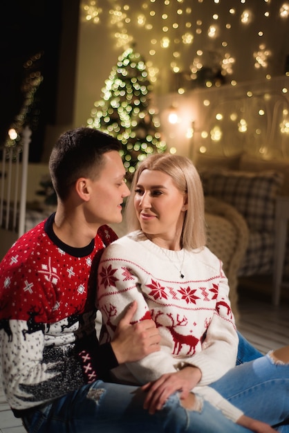 Foto coppia in maglioni a maglia vicino all'albero di natale. uomo e donna nella stanza interna di natale.