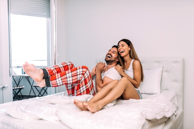 Couple laughing in bed.