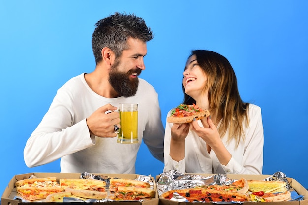 Couple laughing and eating pizza drinks beer smiling happy man and woman happy family lovable couple