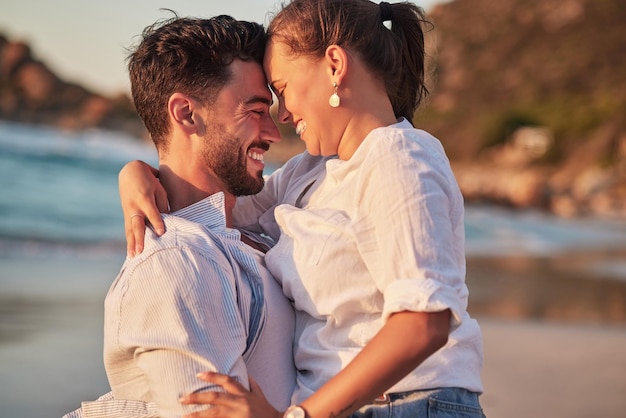 Couple laughing or love hug on beach at sunset for anniversary event honeymoon celebration or engagement Smile happy or comic man and woman bonding in summer by tropical ocean or sea in Portugal