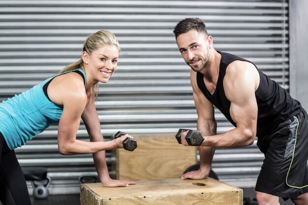 Couple lifting dumbbells together at crossfit gym