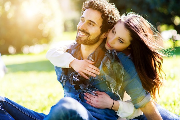 couple looking away while sitting at park