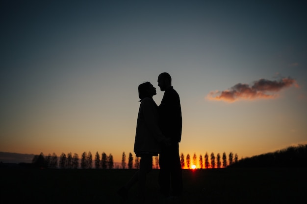 Couple looking at each other and holding hands at amazing sunset