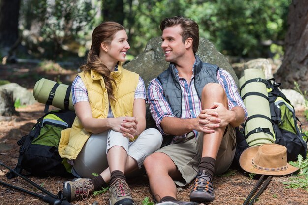 Couple looking face to face while sitting on field during hiking 