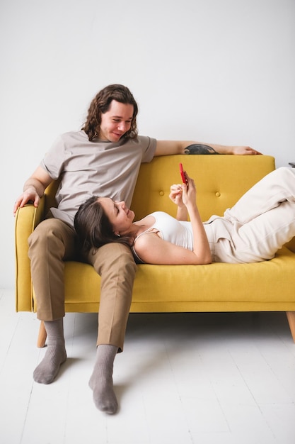 Couple looking at the phone Man and woman lying on the sofa with smartphone use of remote services