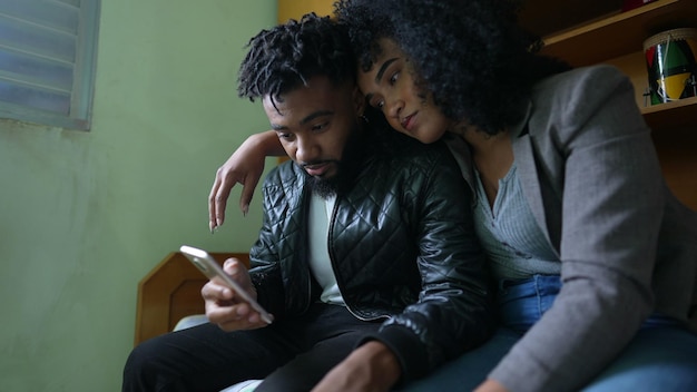 Couple looking at smartphone in bedroom together an african brazilian couple