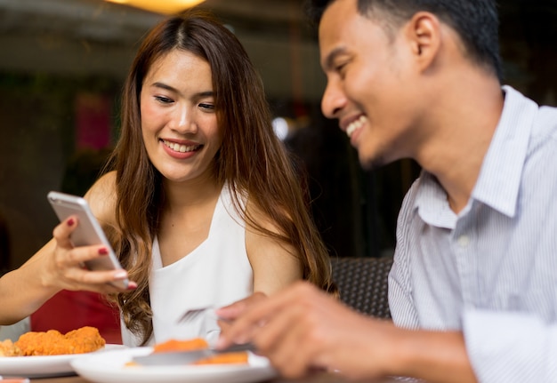 couple looking on smartphone at food shop