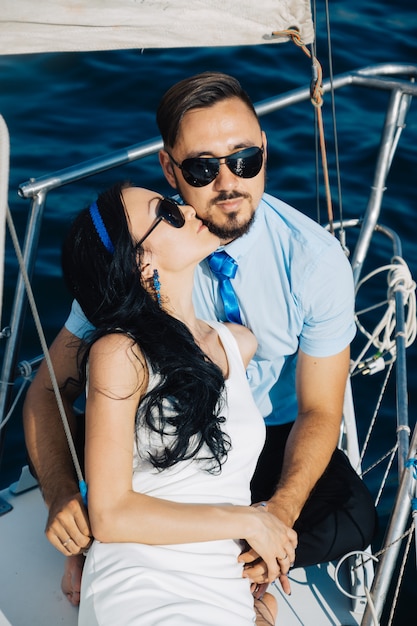 Couple in love are sitting on the deck of the yacht, embracing each other.