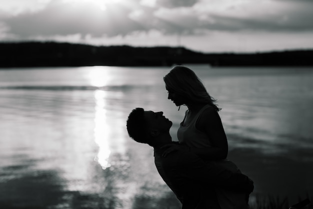 Couple in love back light silhouette at lake sunset